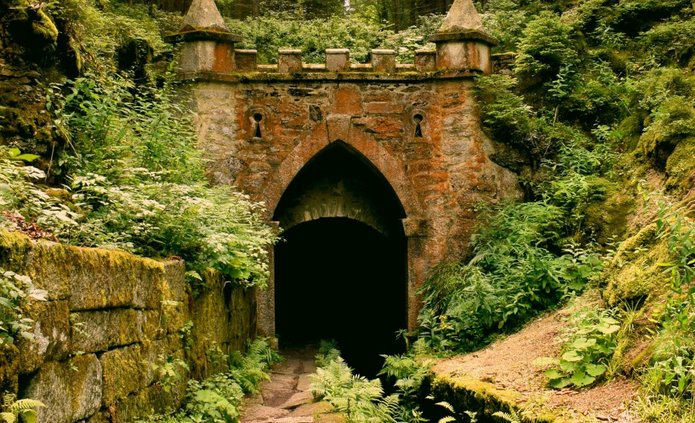 [Translate to English:] Gray concrete tunnel under green trees